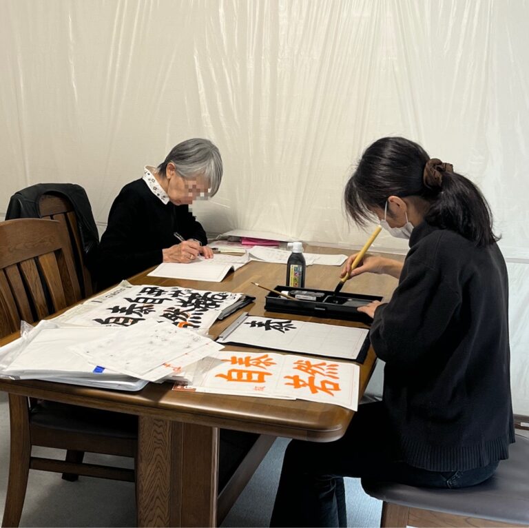 大人の生徒さんが毛筆で清書に取り組む様子